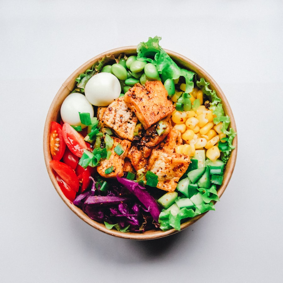 A colorful bowl with grilled chicken, corn, greens, and tomatoes